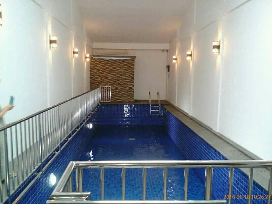 Kolam renang indoor dengan mozaik biru dan railing stainless